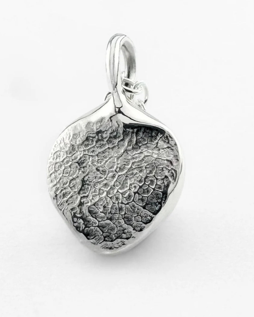 Close up of silver pendant with dog's nose print impression on light grey background
