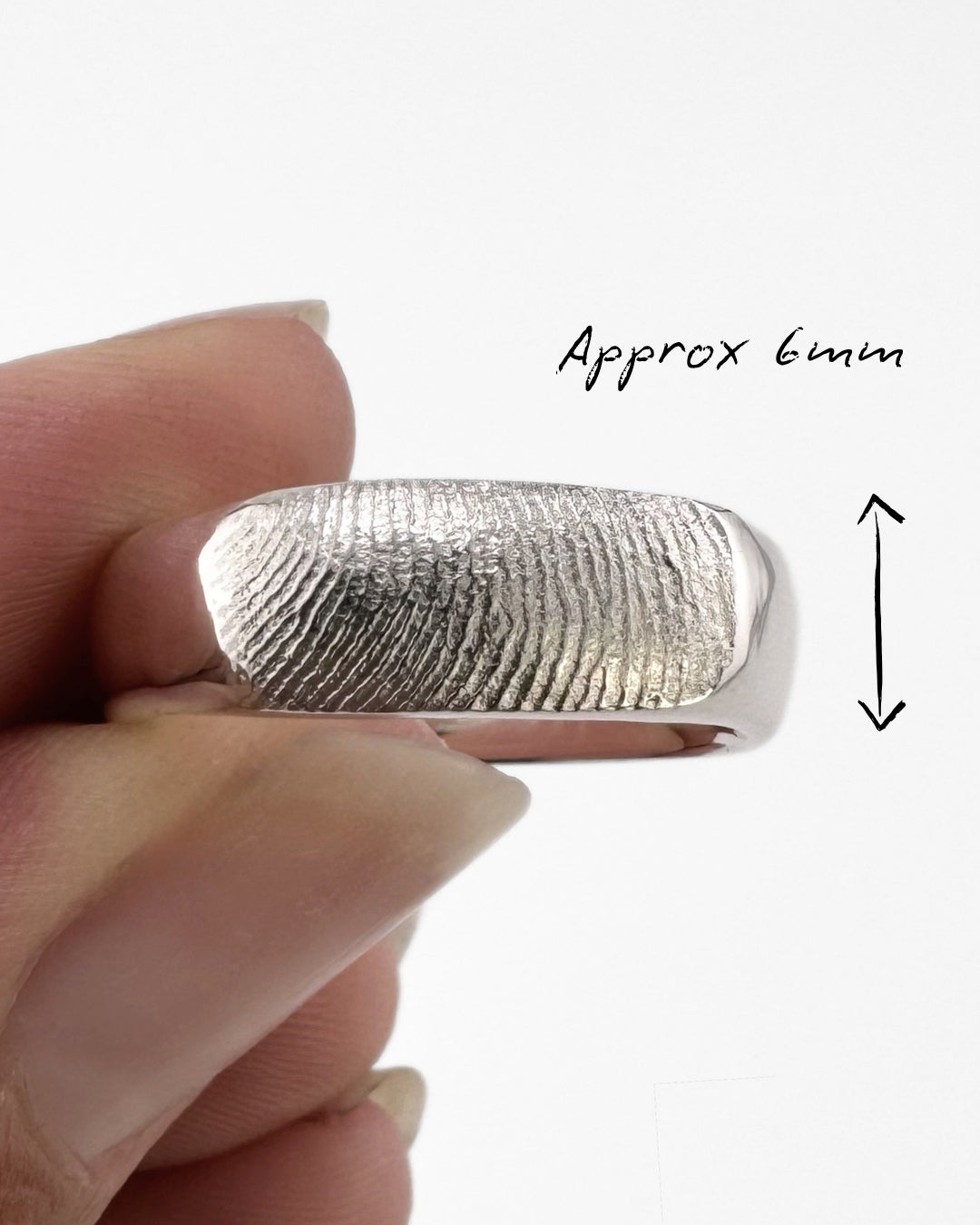 Close up of silver fingerprint ring band on a light grey background