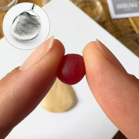 Close up of two people leaving fingerprint impressions on either size of a ball of wax