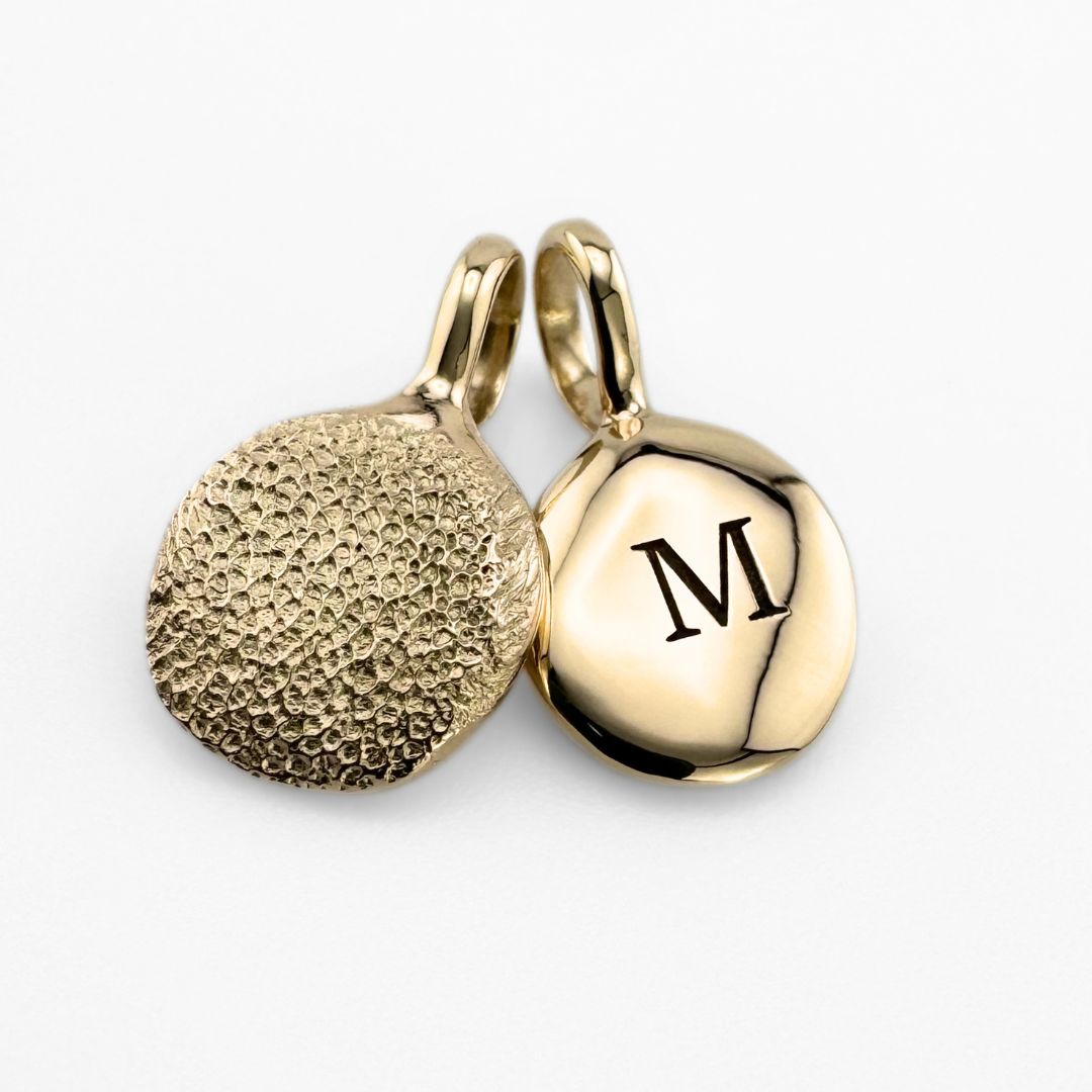 Gold paw print pendant with 'M' laser engraved on the back
