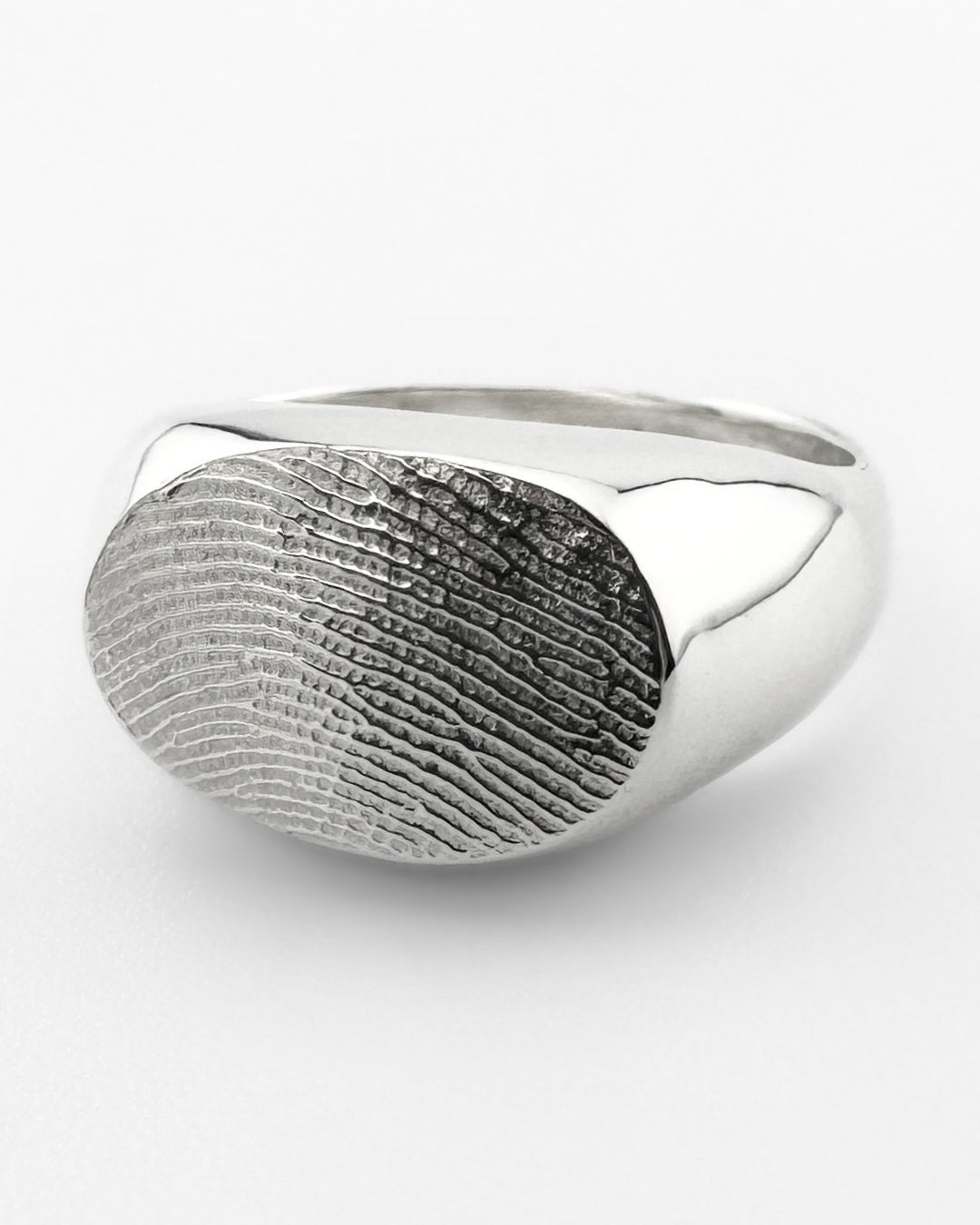 Close-up of a silver oval signet ring with fingerprint impression