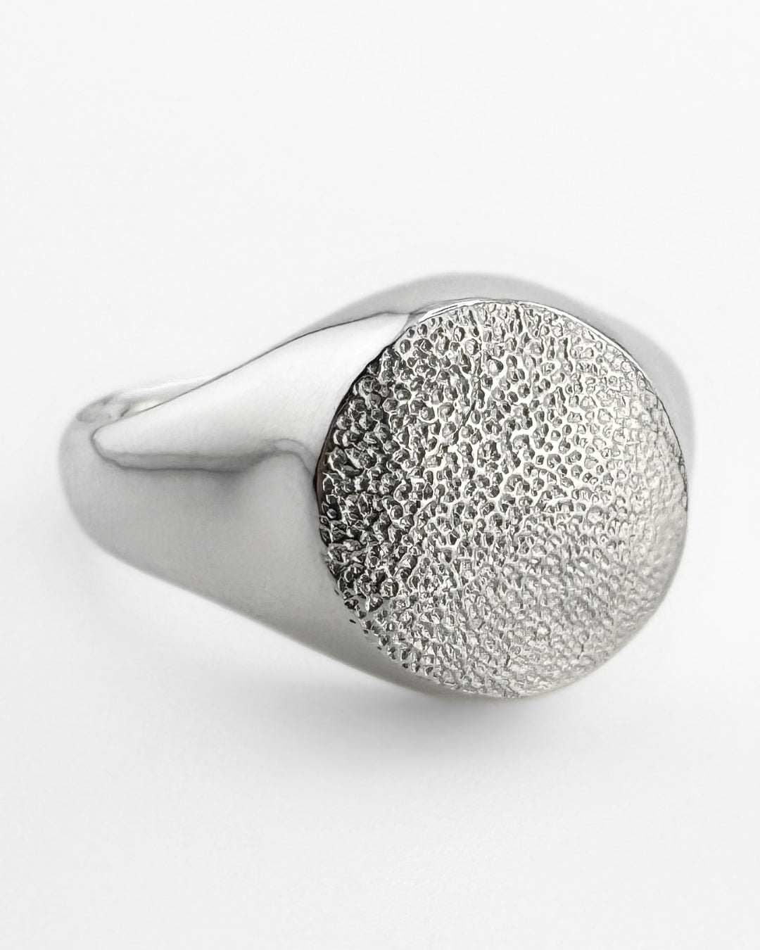 Large silver signet ring with dog's paw print impression on light grey background