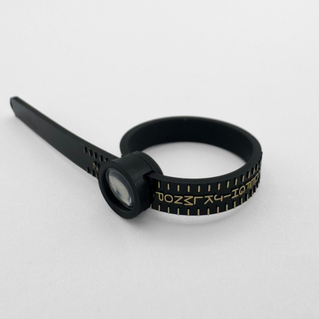 Black plastic ring sizer on light grey background