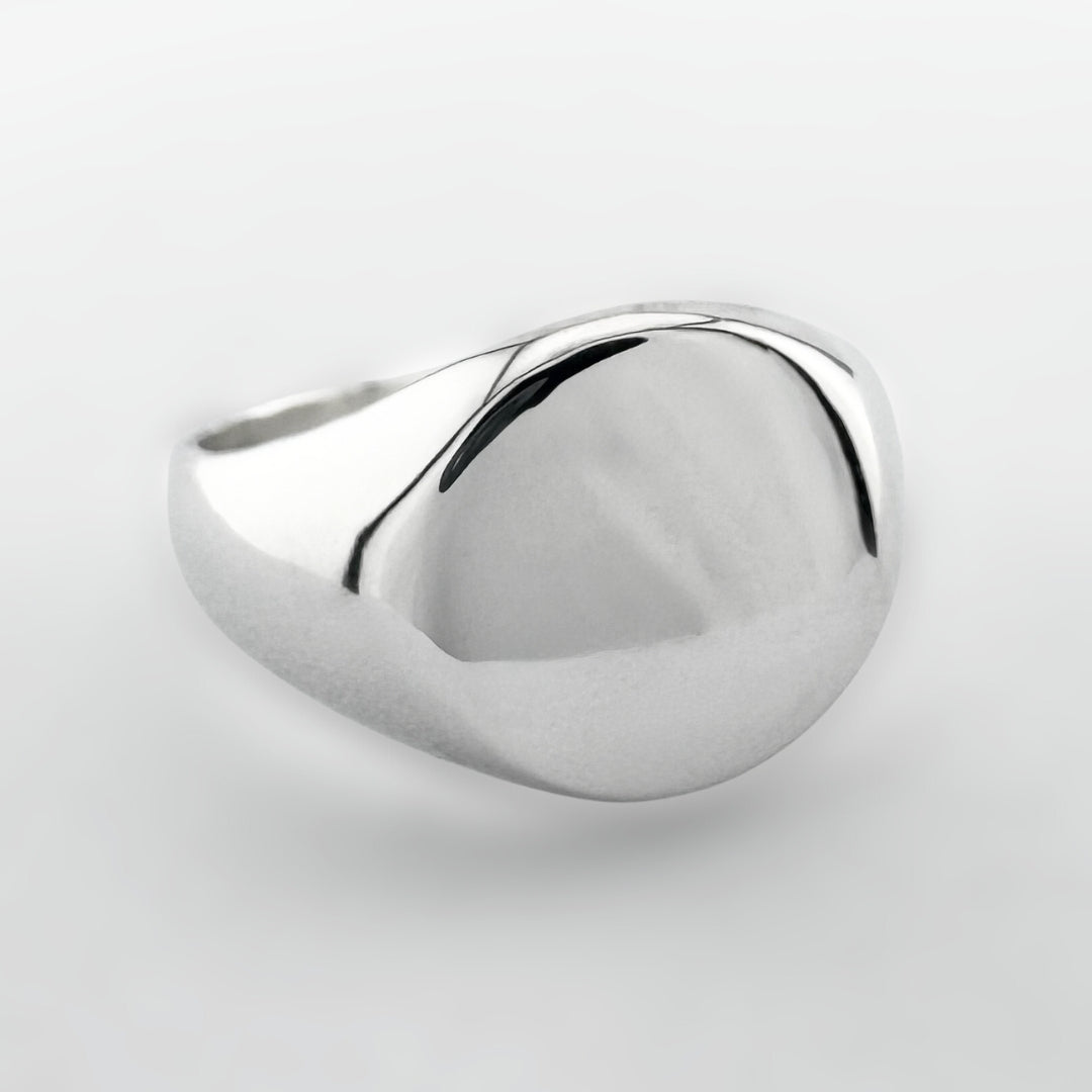 Silver signet ring on a light grey background