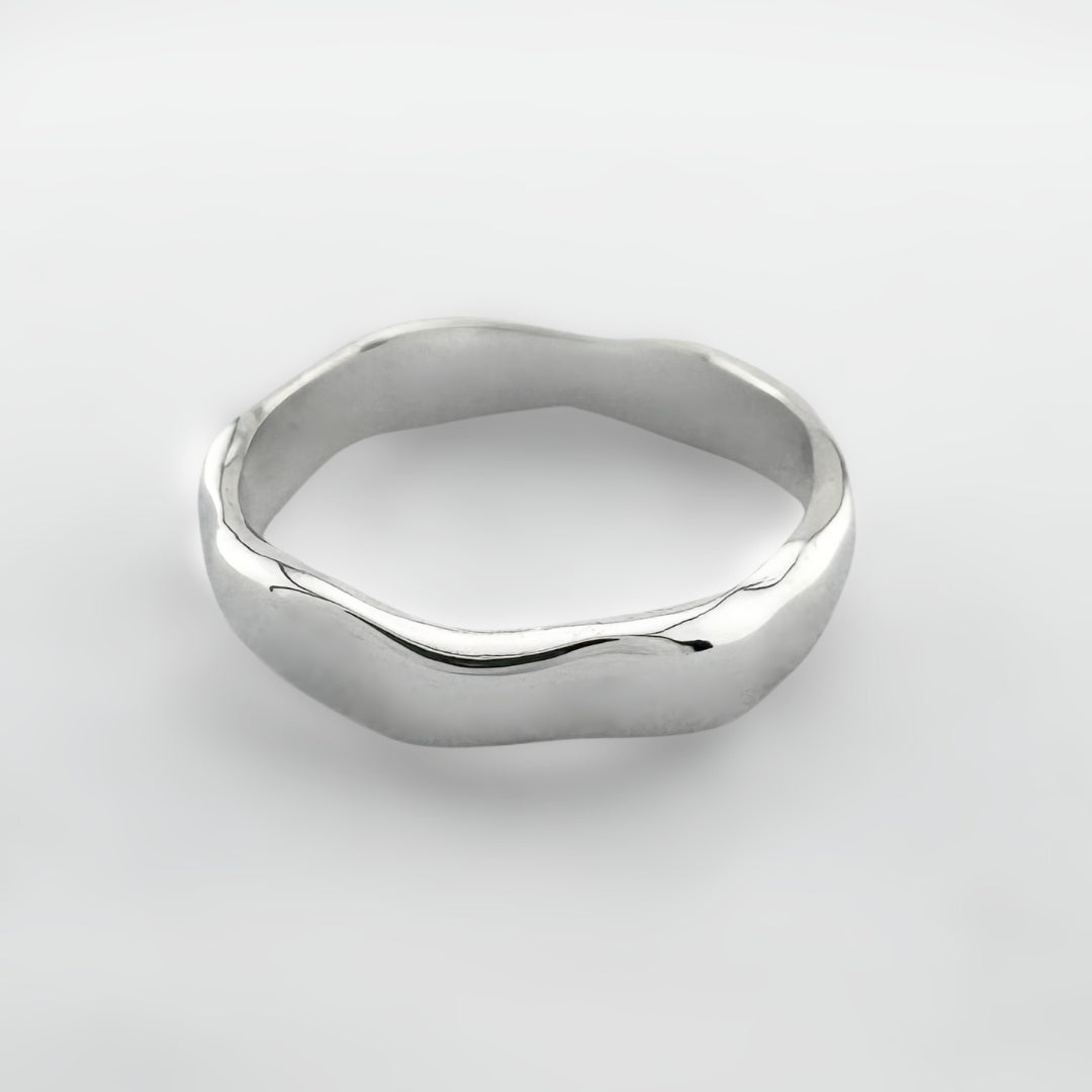 Silver ring with a wave design on a light grey background