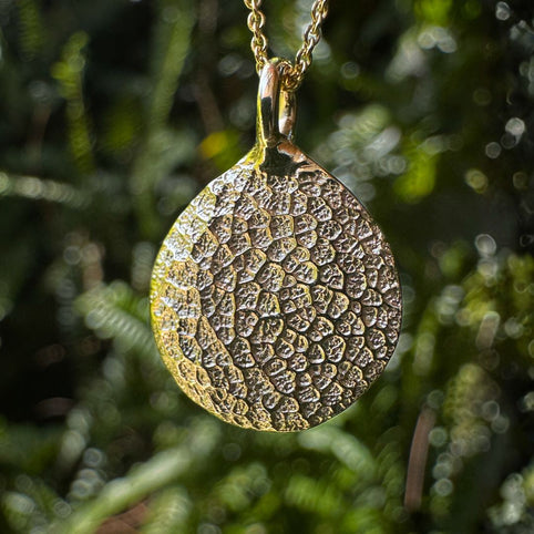 Gold dog's nose print pendant on green leafy background