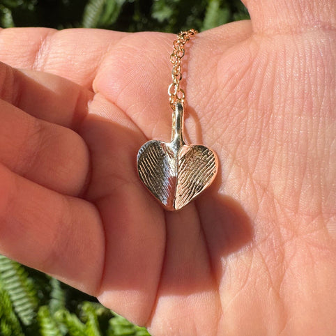 Gold fingerprint necklace in the palm of a hand