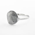 Silver paw print ring on light grey background