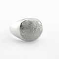 Silver paw print signet ring on light grey background