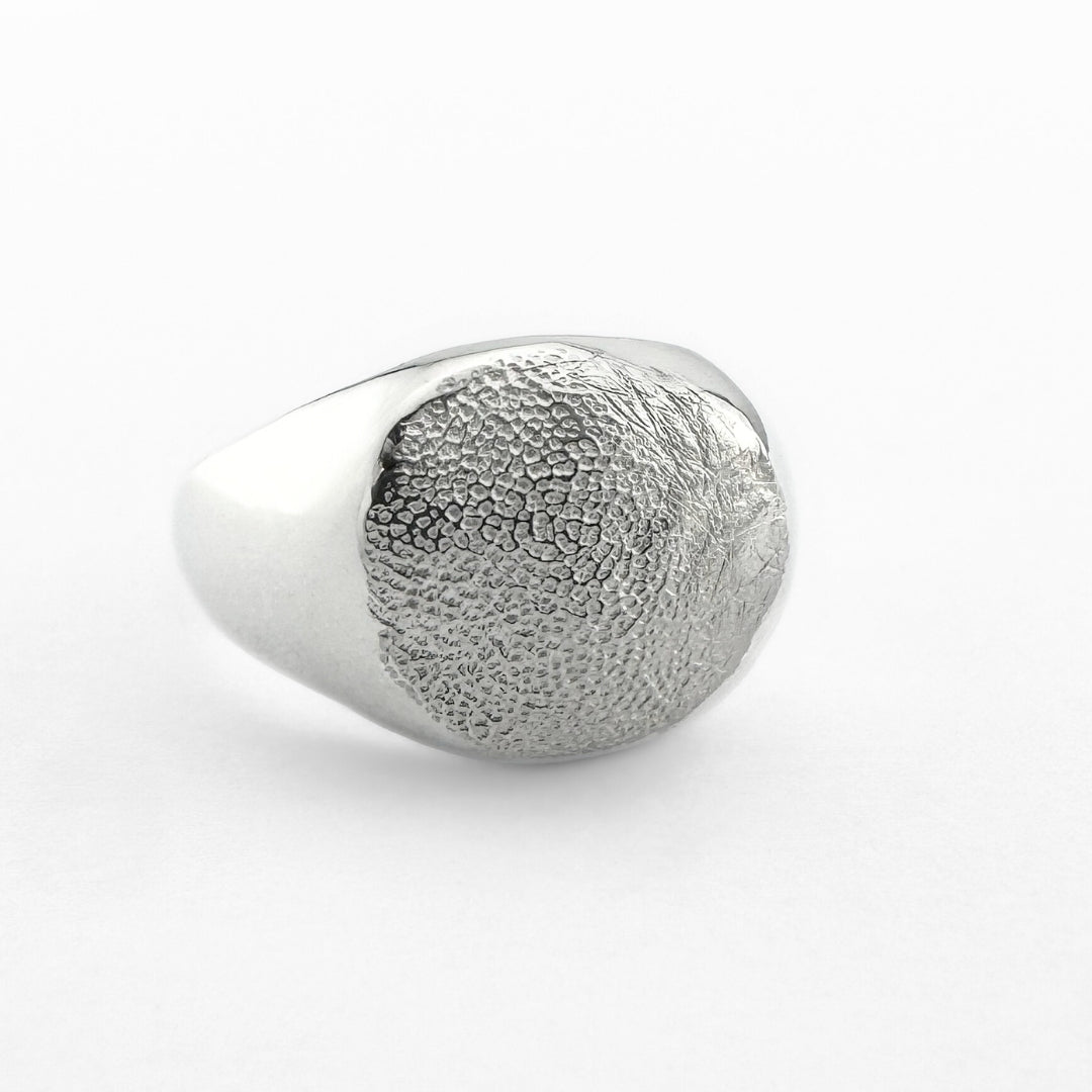 Silver paw print signet ring on light grey background