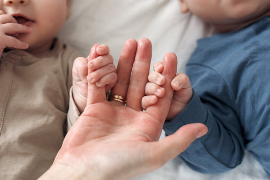 Close up of two babies holding onto mums hands