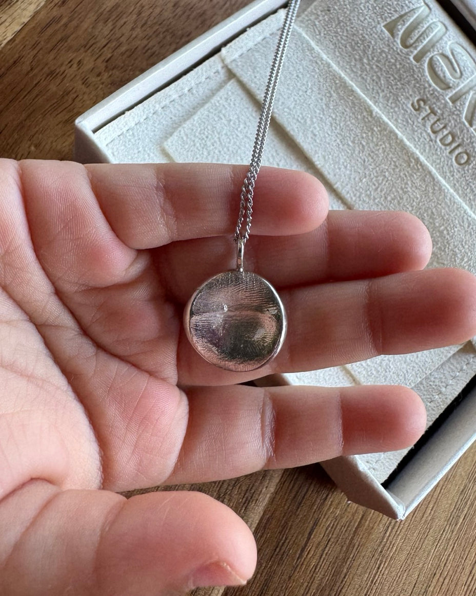 Child holding sterling silver fingerprint pendant