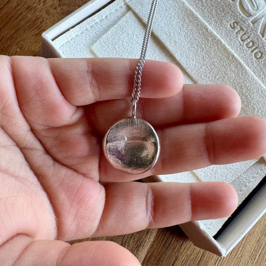 Child holding sterling silver fingerprint pendant