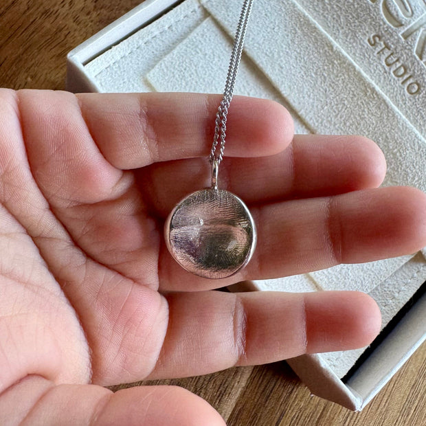 Child holding sterling silver fingerprint pendant