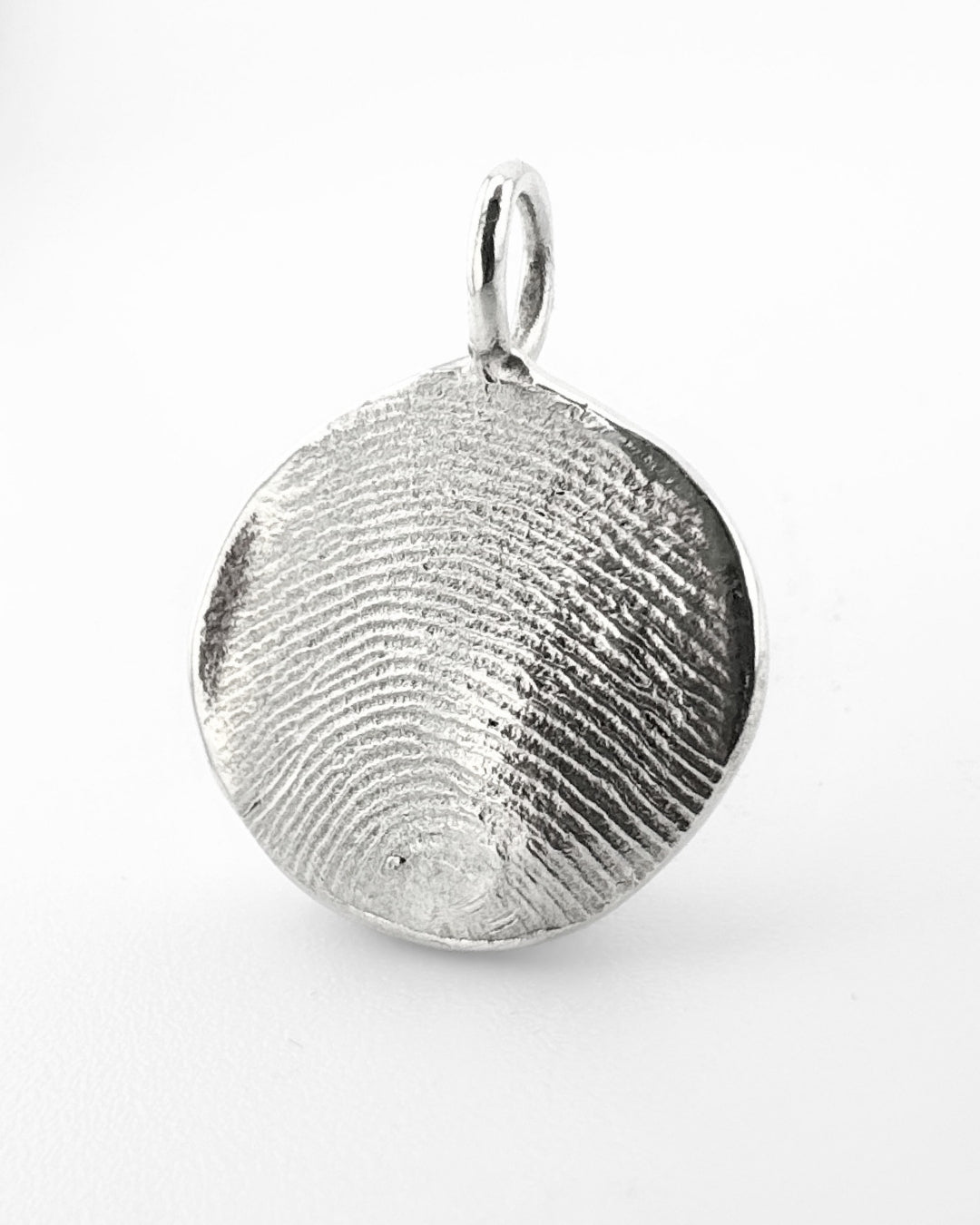 Close up of a silver fingerprint pendant on a light grey background