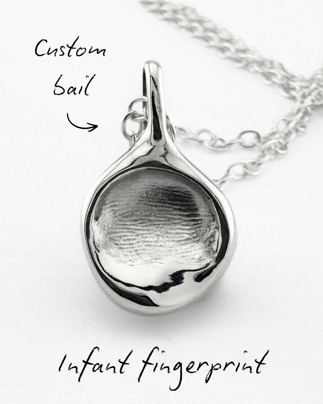 Close up of a silver infant fingerprint pendant on a light grey background