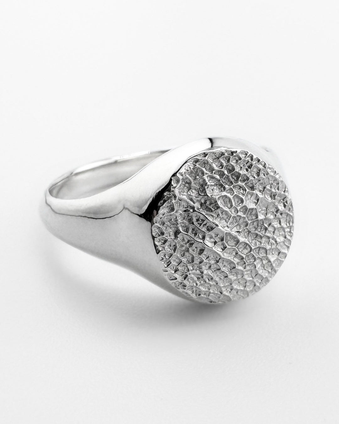 Close up of silver signet ring with dog's nose print impression on light grey background