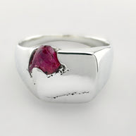 Silver signet ring with a pink sapphire on a white background