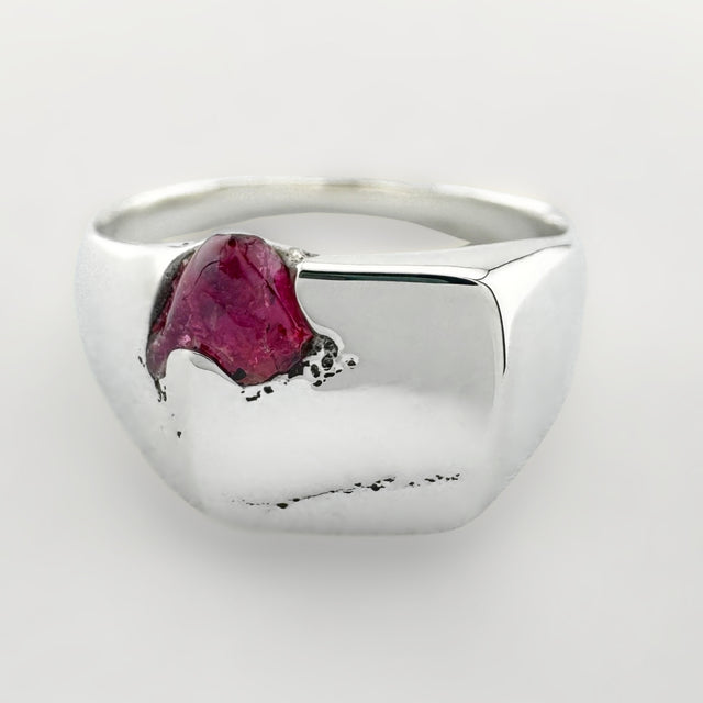 Silver signet ring with a pink sapphire on a white background