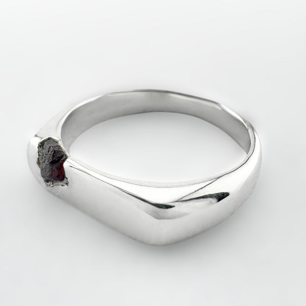 Silver ring with a deep cranberry sapphire on a white background