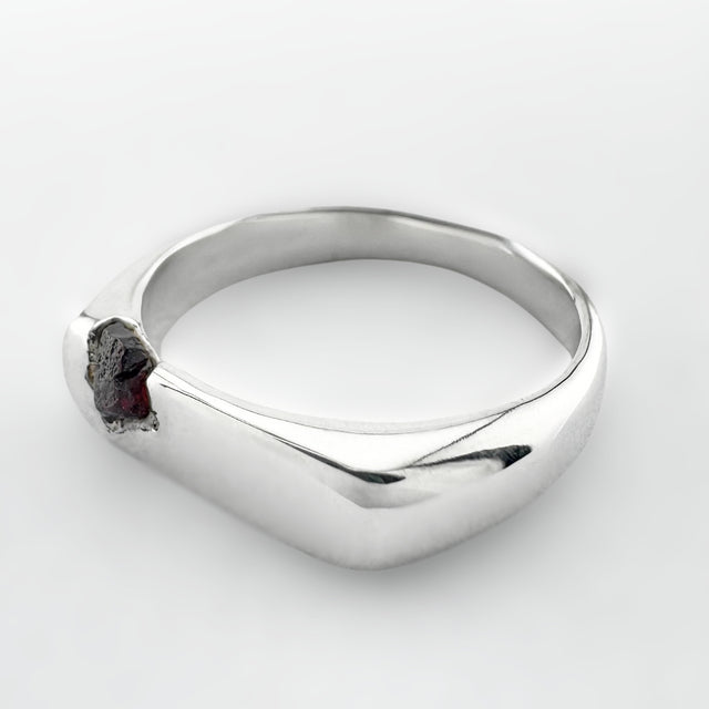 Silver ring with a deep cranberry sapphire on a white background