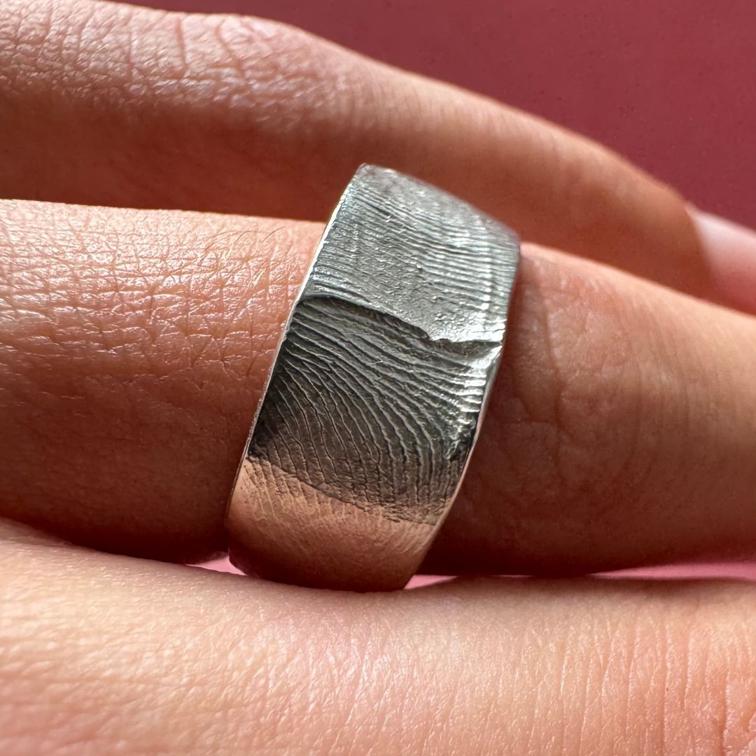 A person wearing a sterling silver fingerprint impression ring band