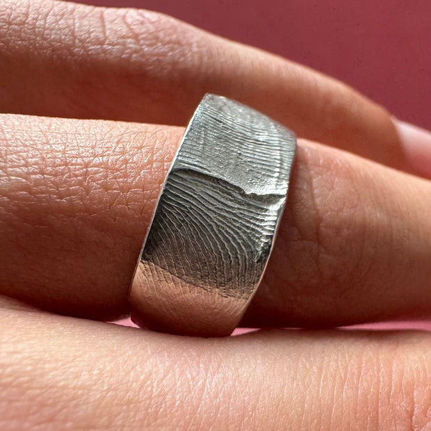 A person wearing a sterling silver fingerprint impression ring band