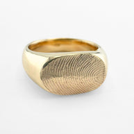 Gold fingerprint signet ring on light grey background