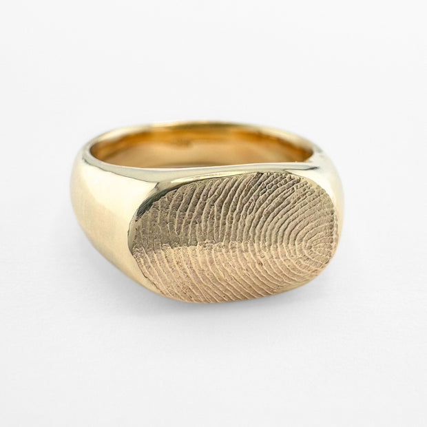 Gold fingerprint signet ring on light grey background