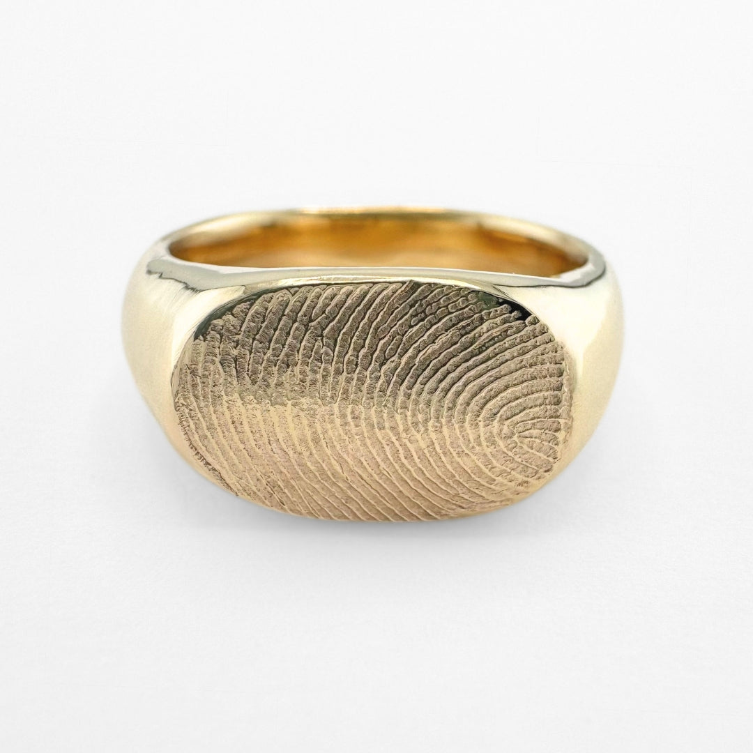 Gold fingerprint signet ring on light grey background