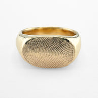 Gold fingerprint signet ring on light grey background