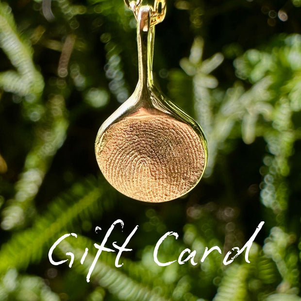 Gold fingerprint necklace on green leafy background with white text 'Gift Card'