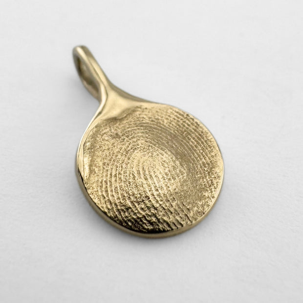 Gold fingerprint pendant on light grey background
