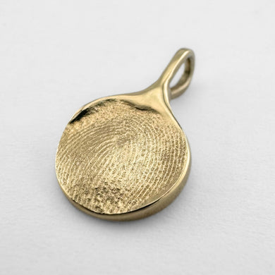 Gold fingerprint pendant on light grey background