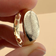 Close up of gold fingerprint signet ring on yellow background