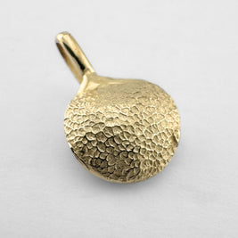 Gold dogs paw print pendant on light grey background