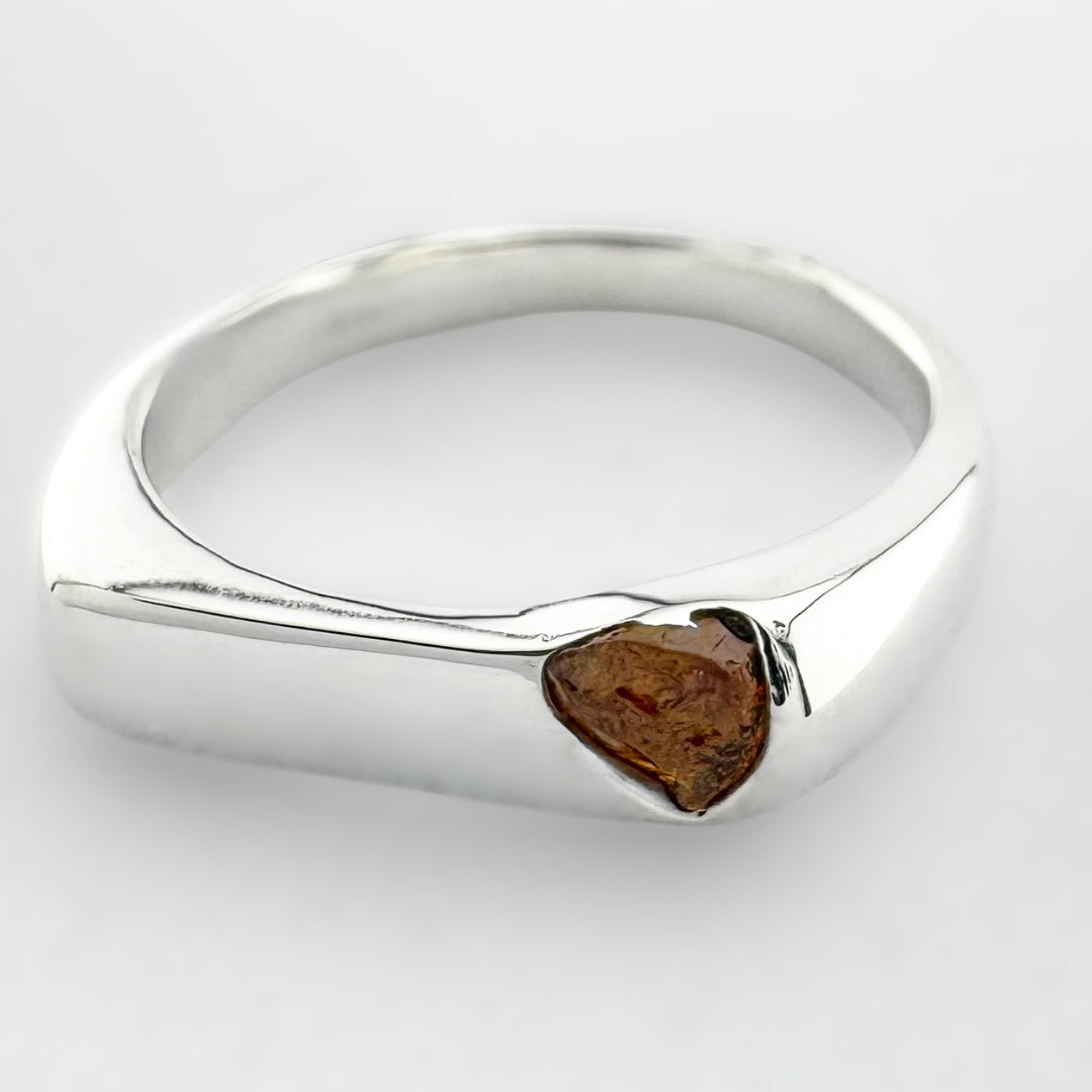 Thin silver signet ring with a honey coloured sapphire on a light grey background