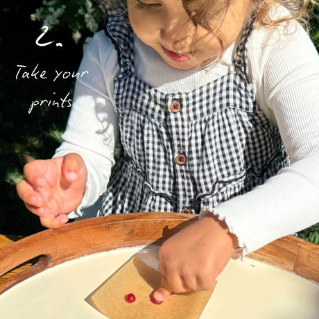 Child outside in a garden pressing her finger into a red ball of wax