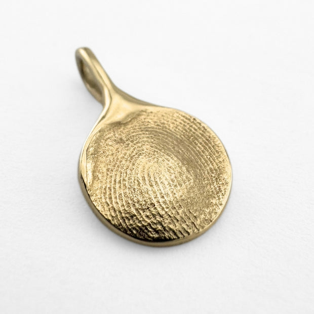 Gold fingerprint pendant on light grey background