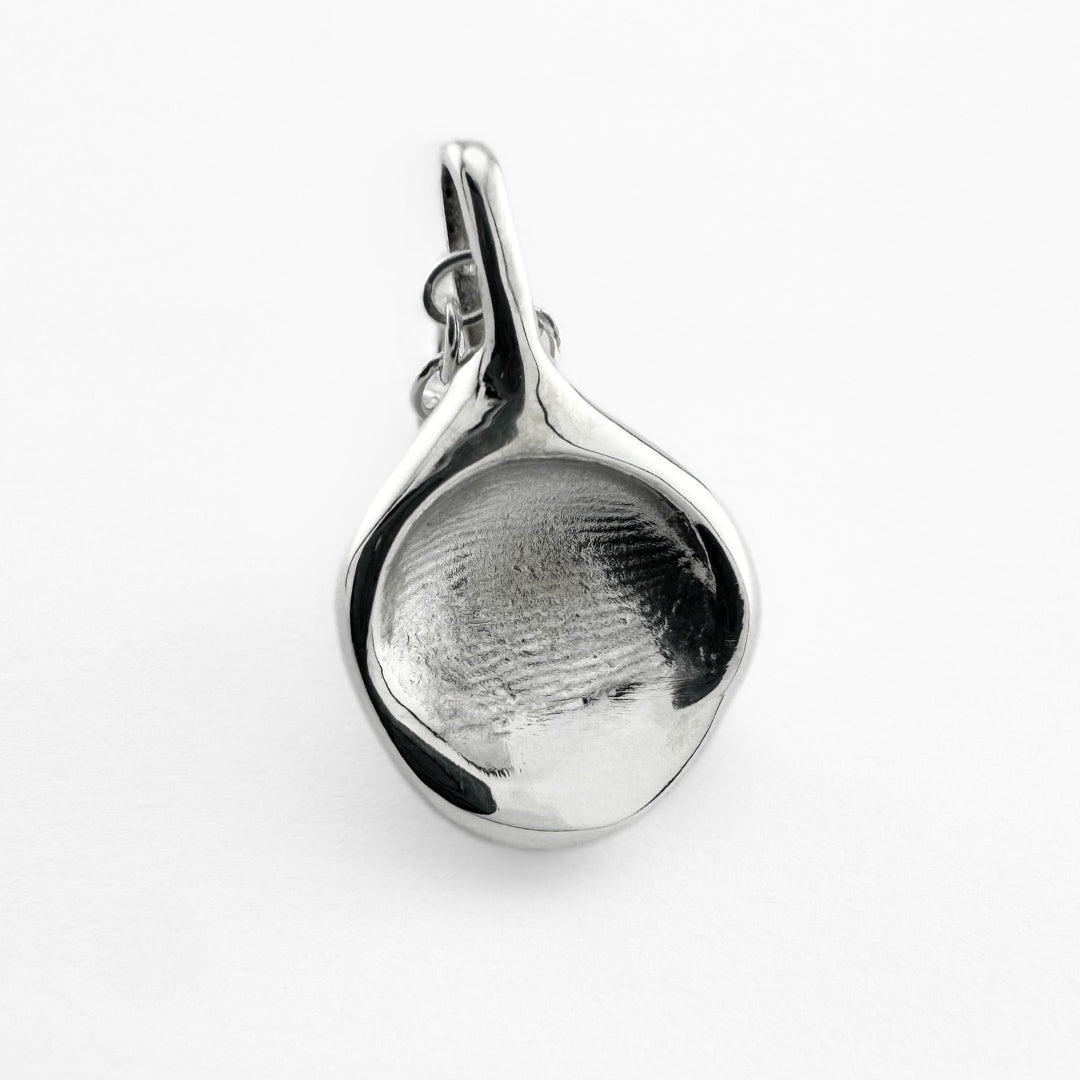 Close up of silver fingerprint pendant on light grey background