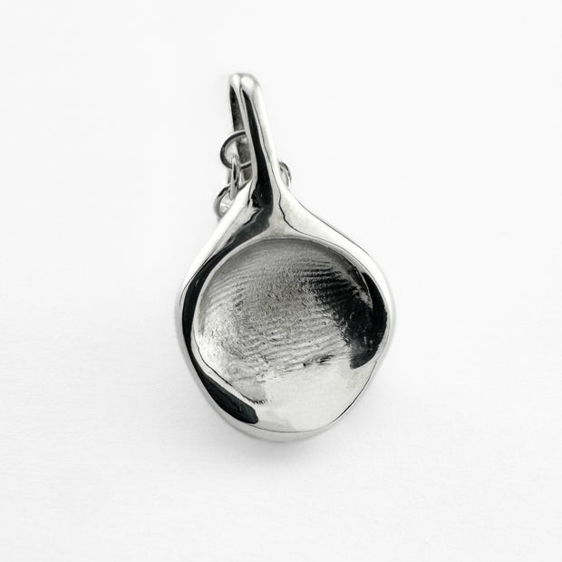 Close up of silver fingerprint pendant on light grey background