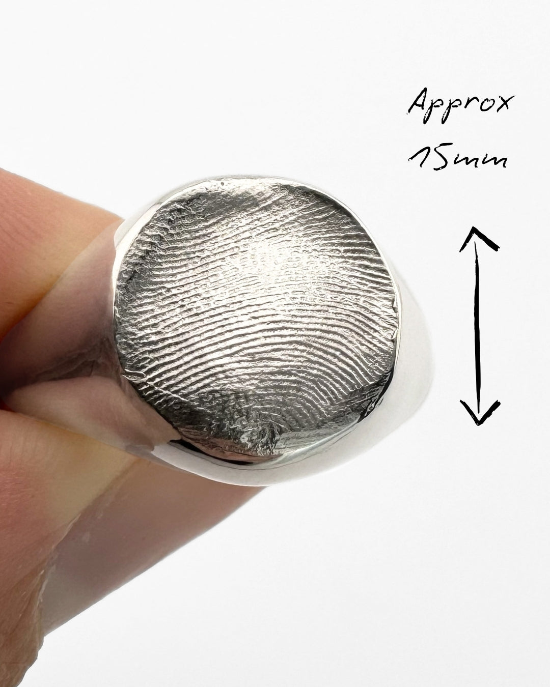 Close-up of large silver signet ring with fingerprint impression