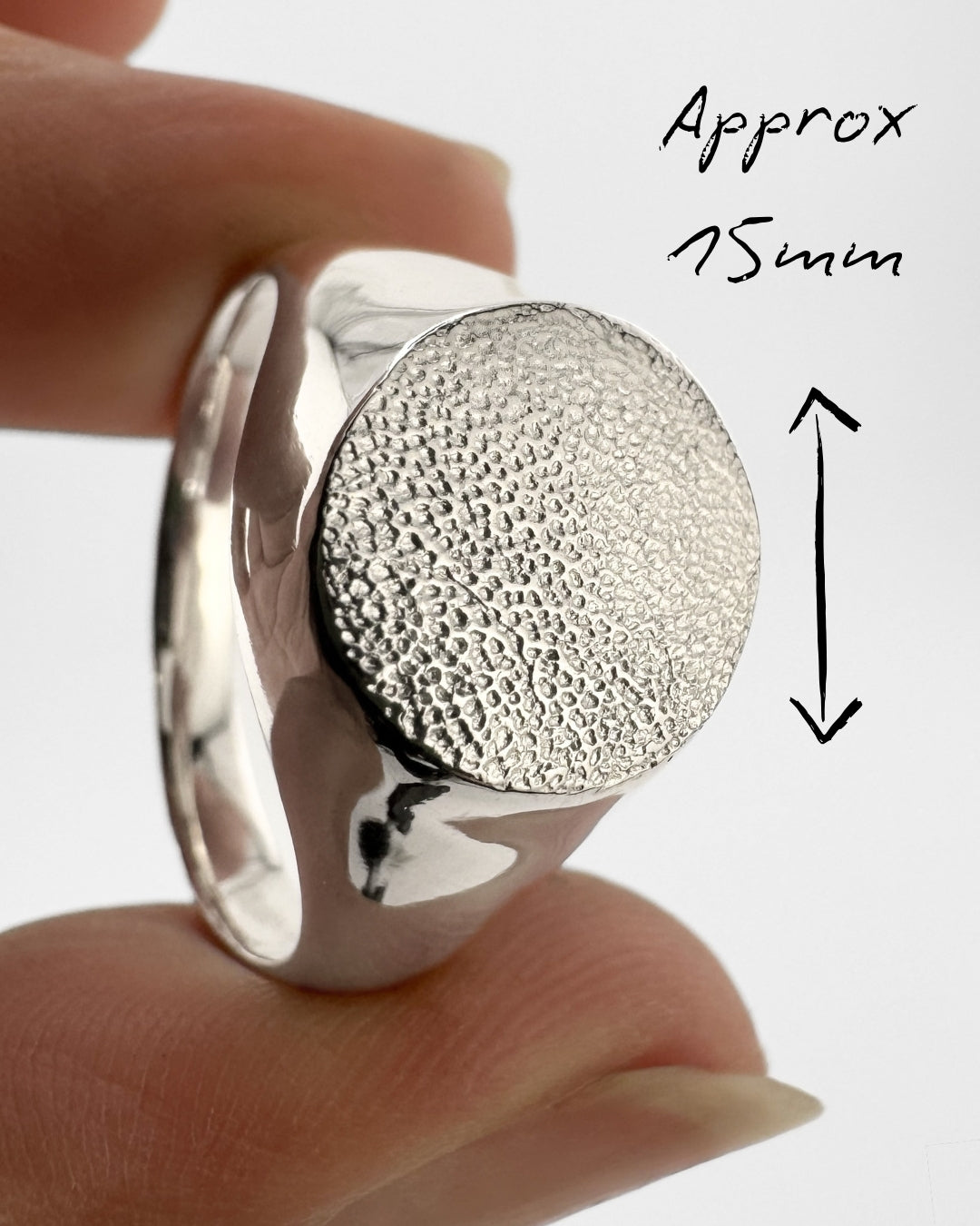 Large silver signet ring with dog's paw print impression on light grey background
