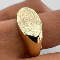 Close up of someone wearing a gold fingerprint signet ring