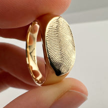 Close up of someone holding a gold fingerprint signet ring