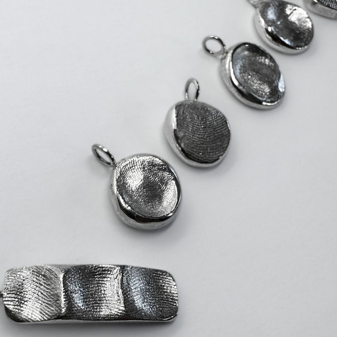 Six sterling silver fingerprint pendants on white background