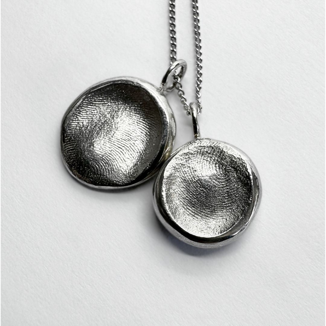 Two sterling silver fingerprint pendants on a silver chain