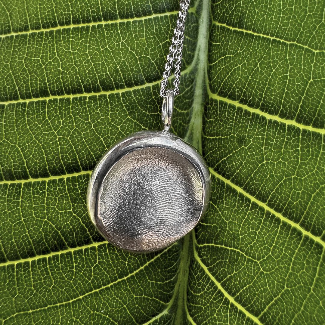 Sterling silver fingerprint necklace on green leaf