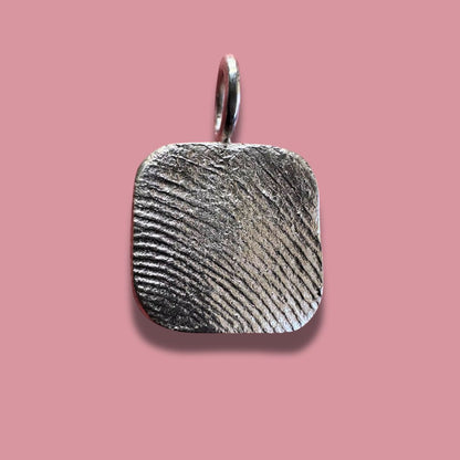 Square sterling silver fingerprint pendant on pink background