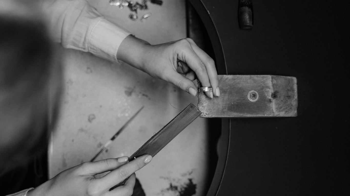 Lady hand filing a silver ring on a jewellery peg